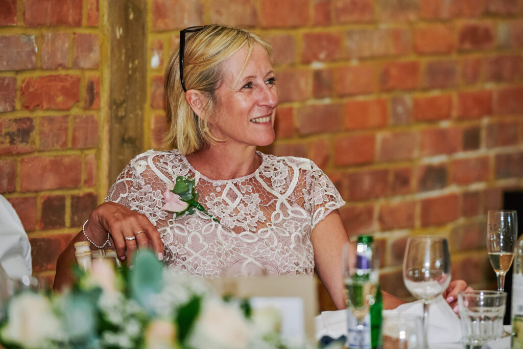wedding guest laughing whilst sat in rustic wedding room