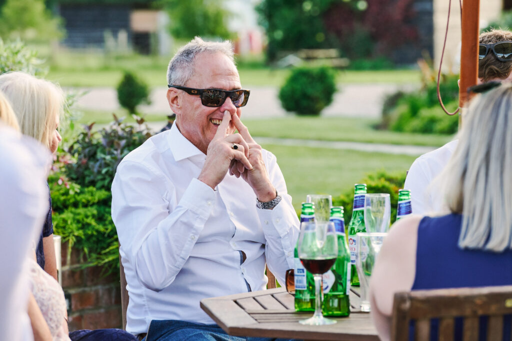 male wedding guest laughing whilst sticking his fingers up his nose