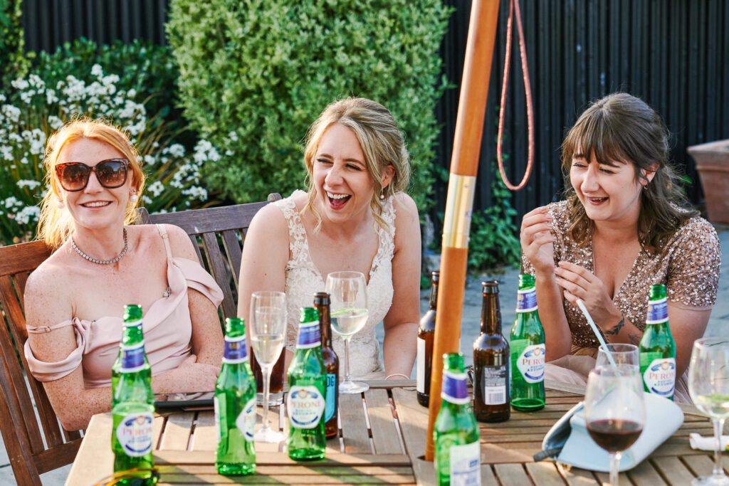 natural wedding photography showing bride & guests laughing in the sun