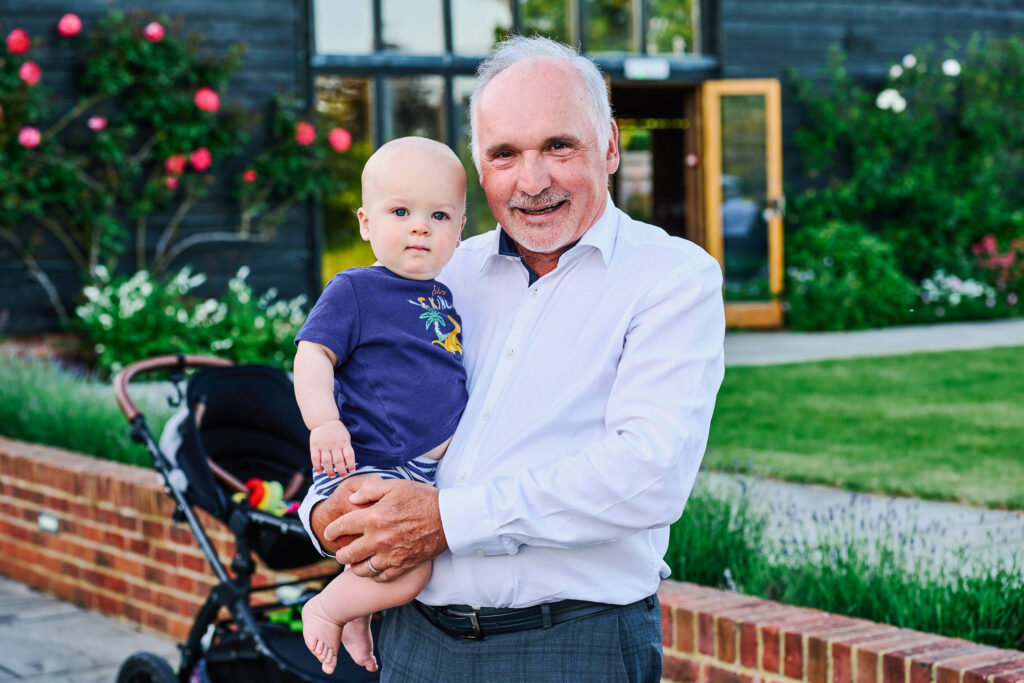 wedding guest smiling whilst holding his grandson