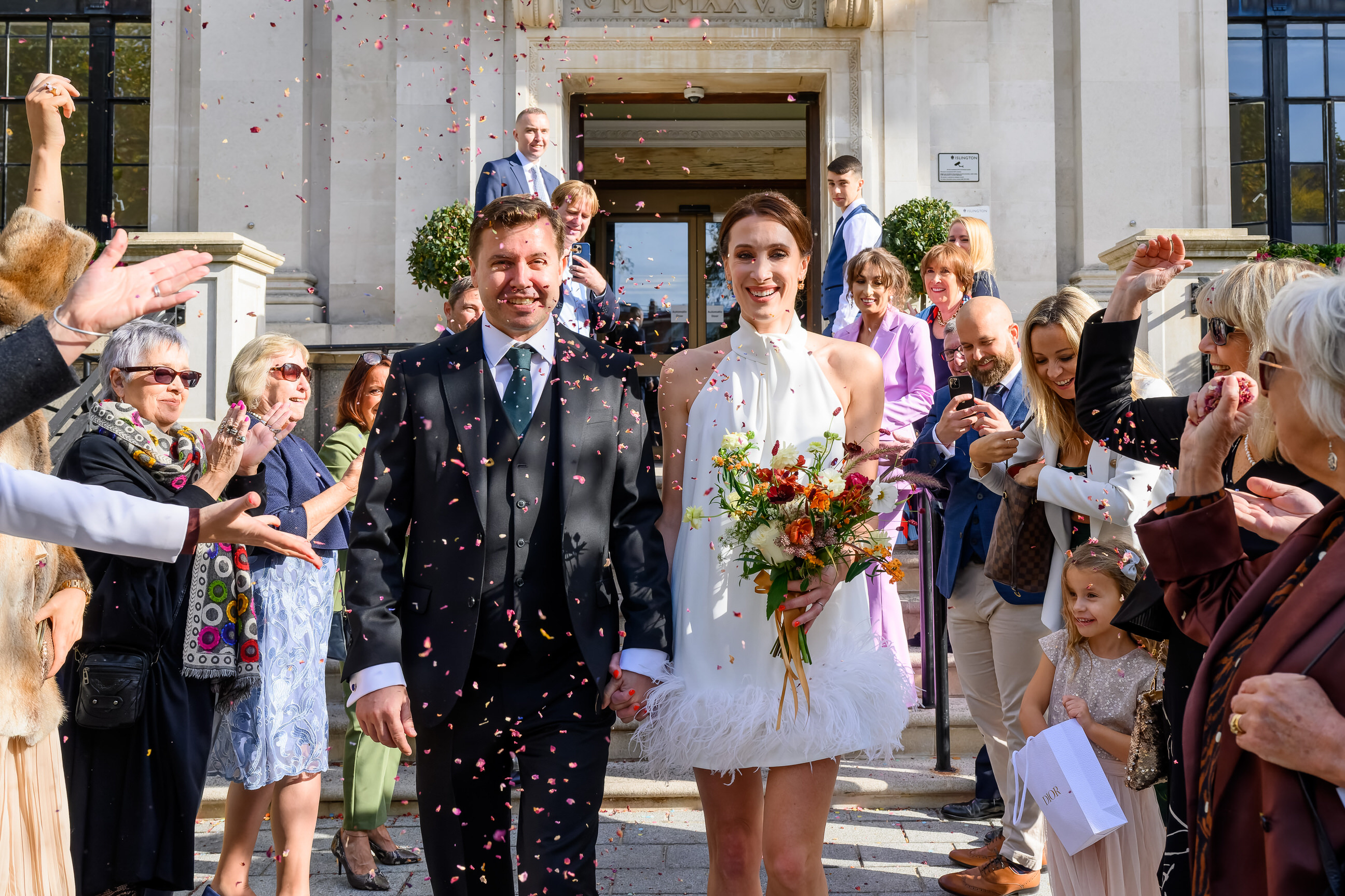 bride and groom walking through confetti in front of Islington Town Hall