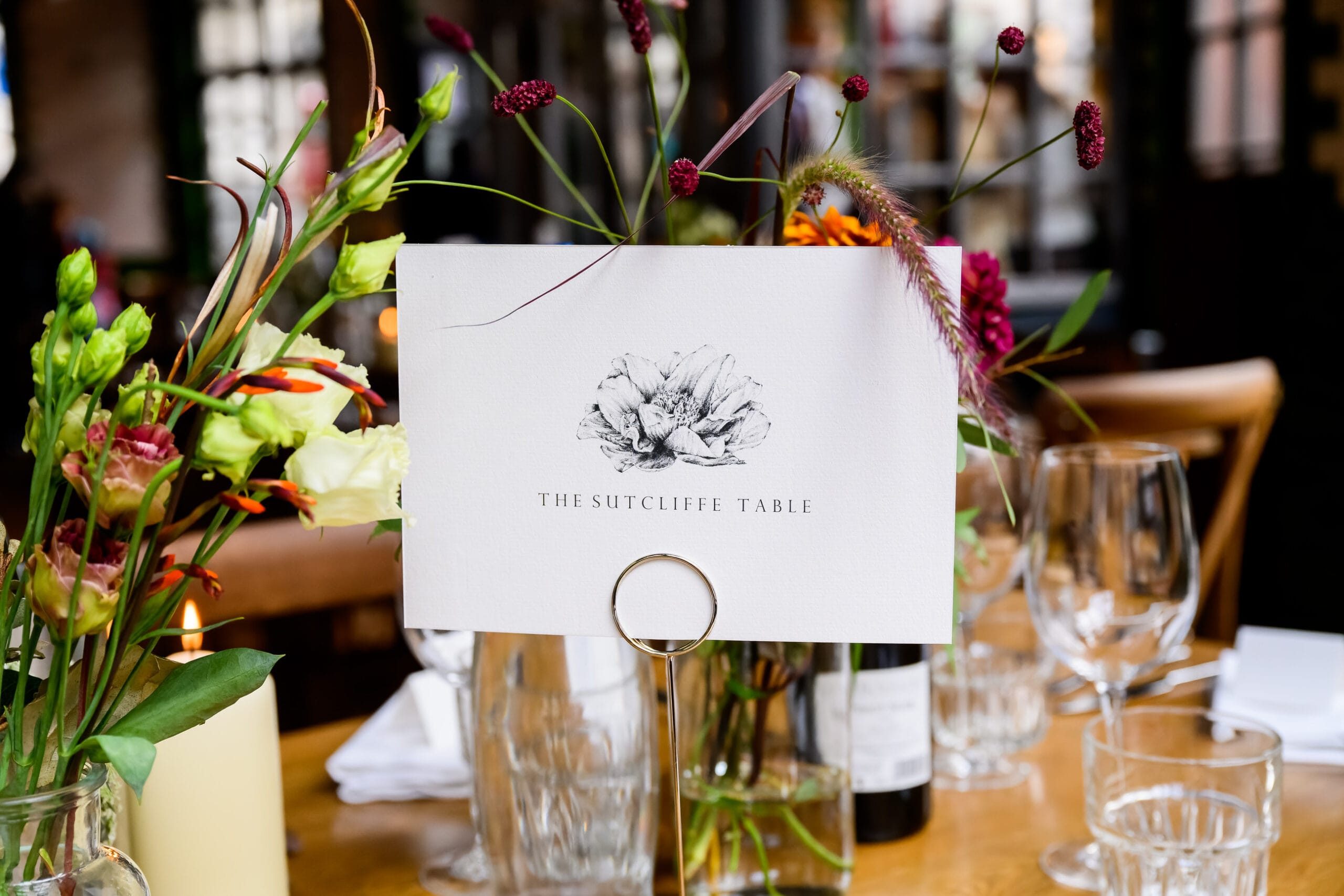 Serial killer wedding table name surrounded by flowers at London pub wedding