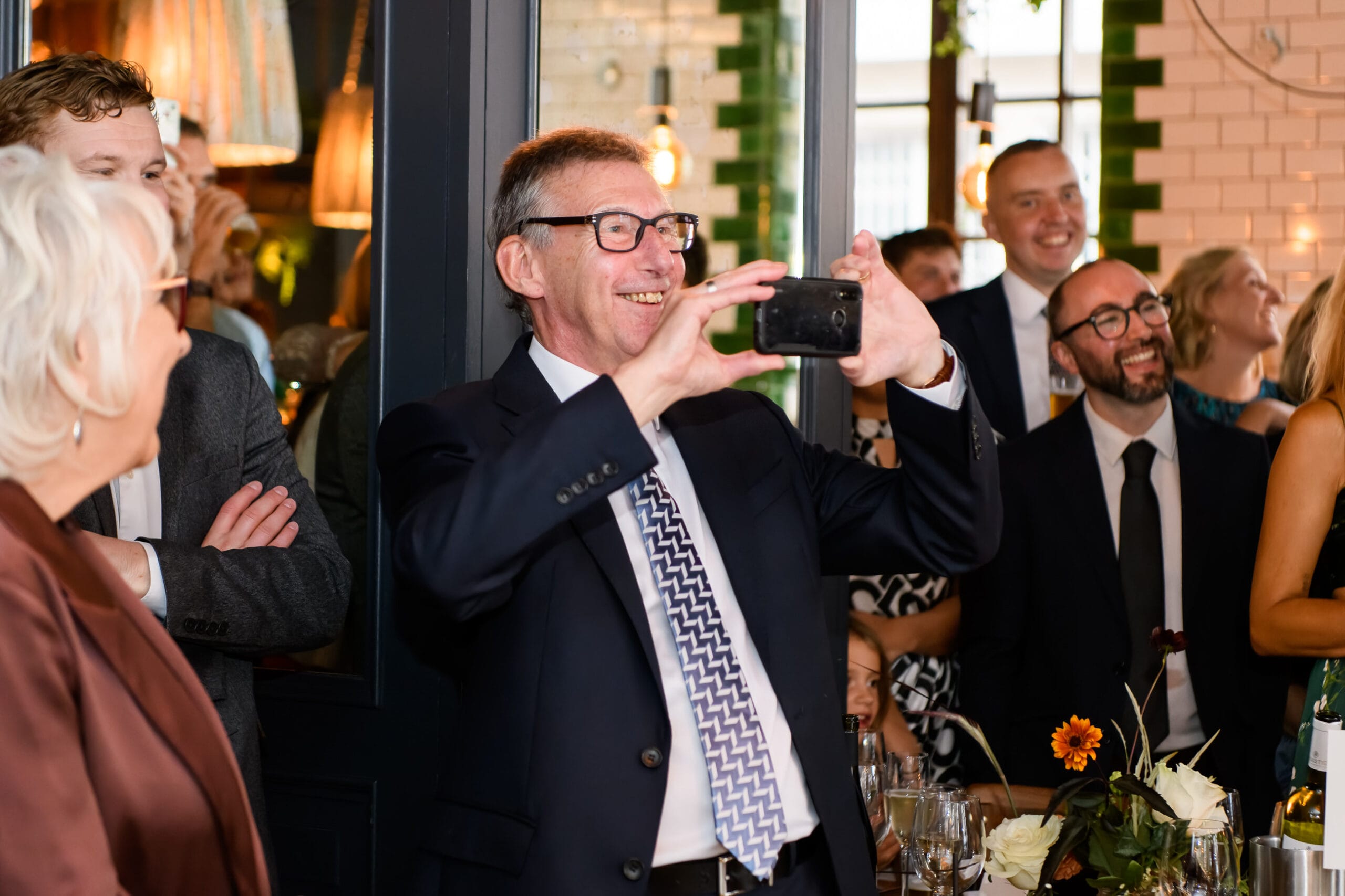 Wedding guest taking a photo and smiling during London pub wedding