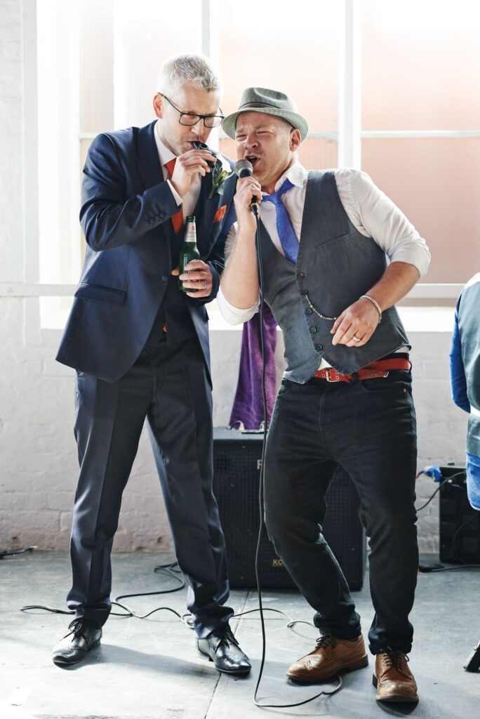 Groom and performer singing together during unique warehouse wedding