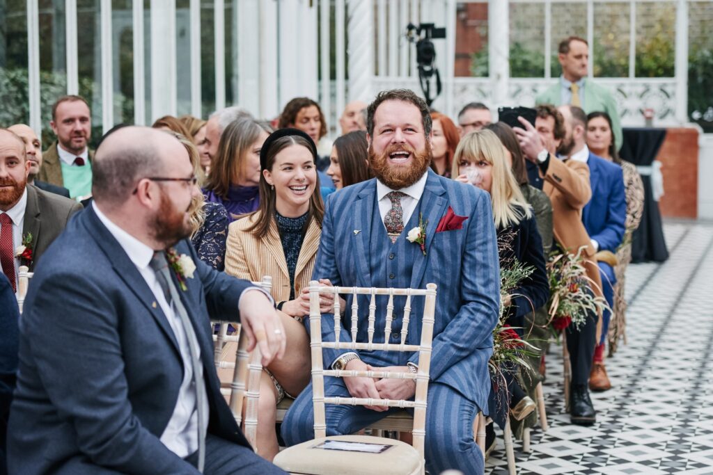 wedding guests laughing during winter wedding at The Horniman Museum conservatory