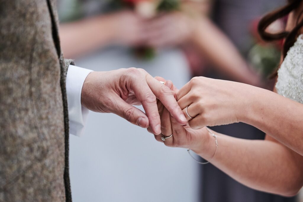 close up of hands exchanging wedding rings
