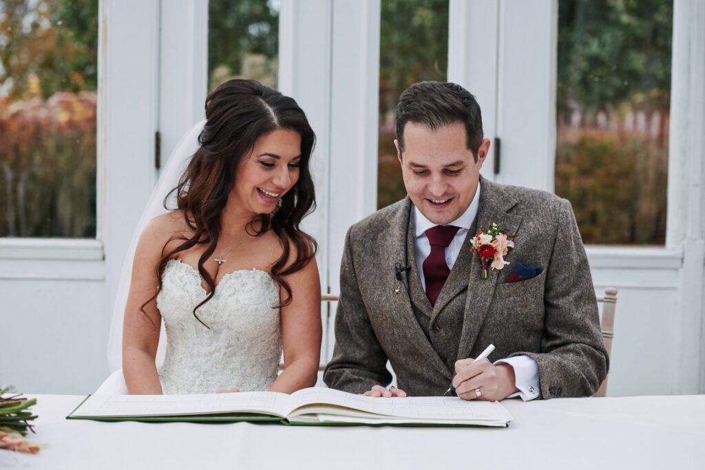 bride and groom signing the register  at The Horniman Museum conservatory