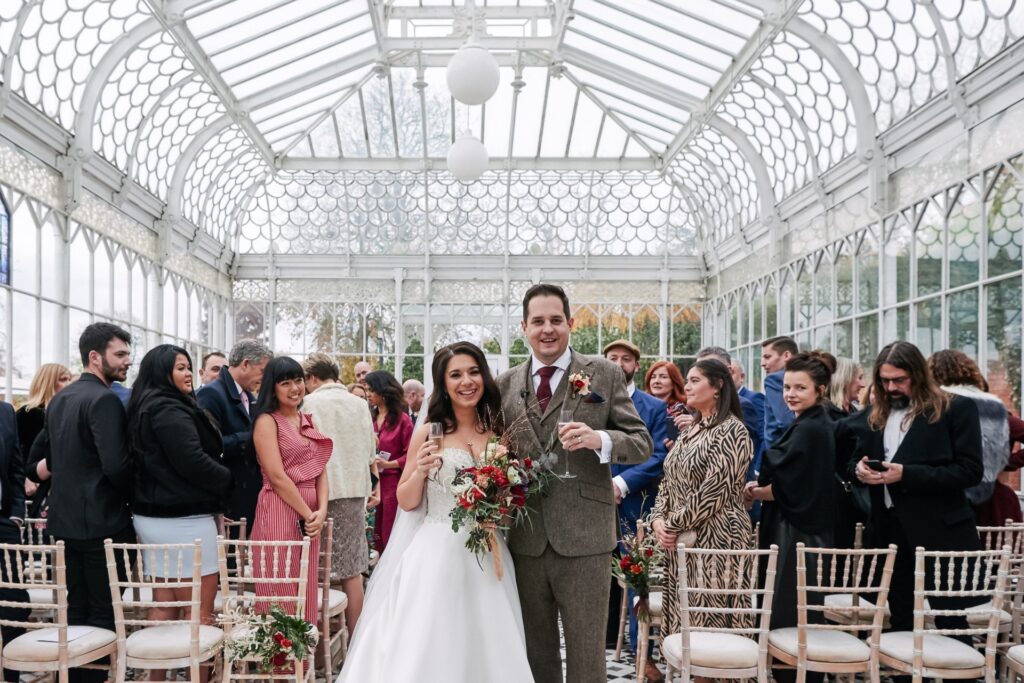 Happy bride and groom with wedding guests in the conservatory at The Horniman Museum