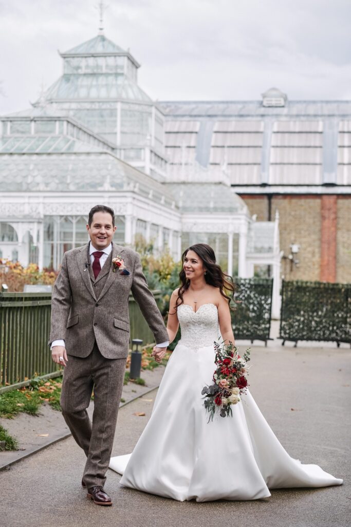 bride and groom walking together in front of the conservatory at The Horniman museum. 