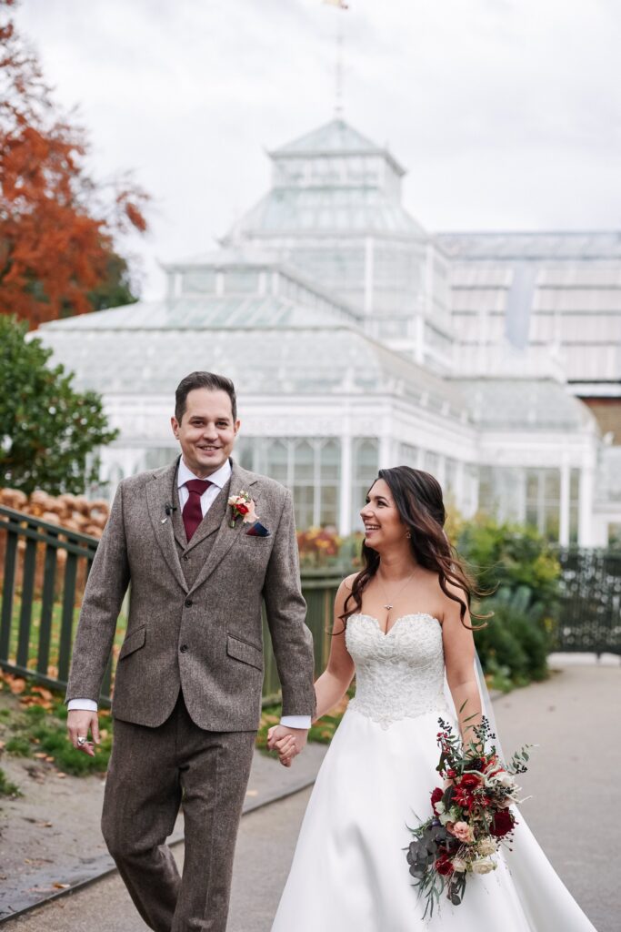 bride and groom walking together in front of the conservatory at The Horniman museum. 