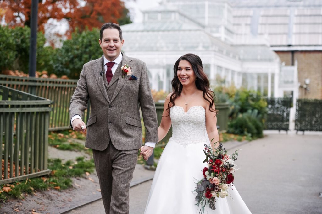 bride and groom walking together in front of the conservatory at The Horniman museum. 
