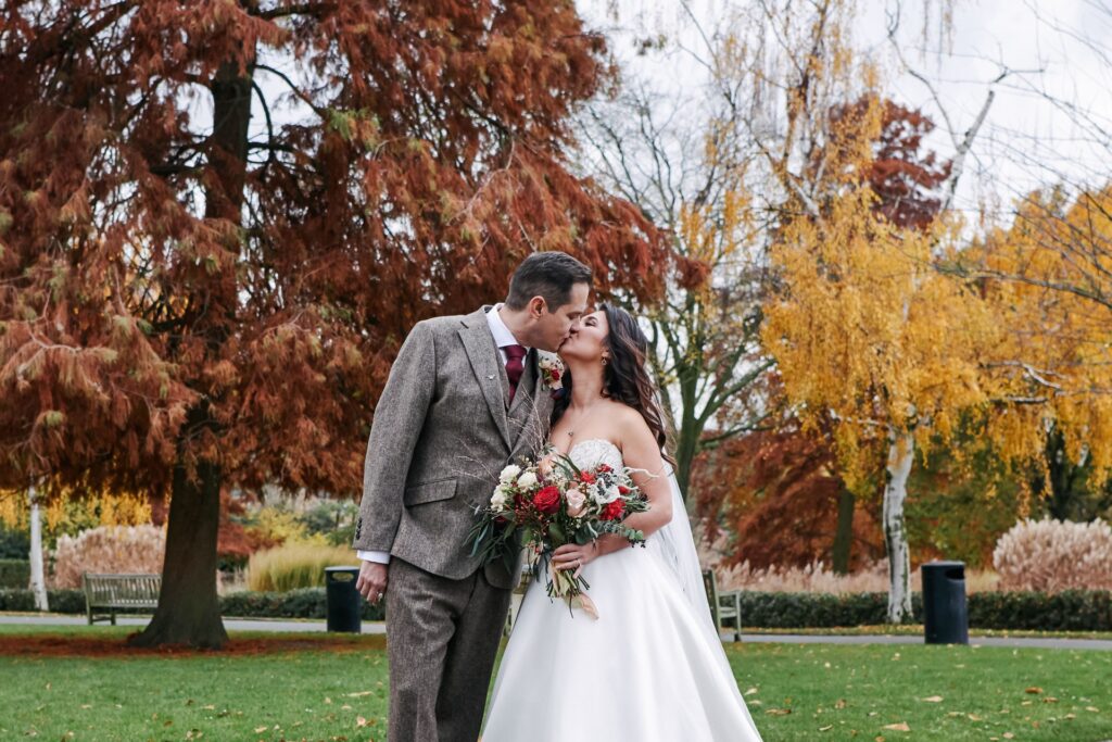 bride and groom kissing in the autumnal gardens at The Horniman museum. 