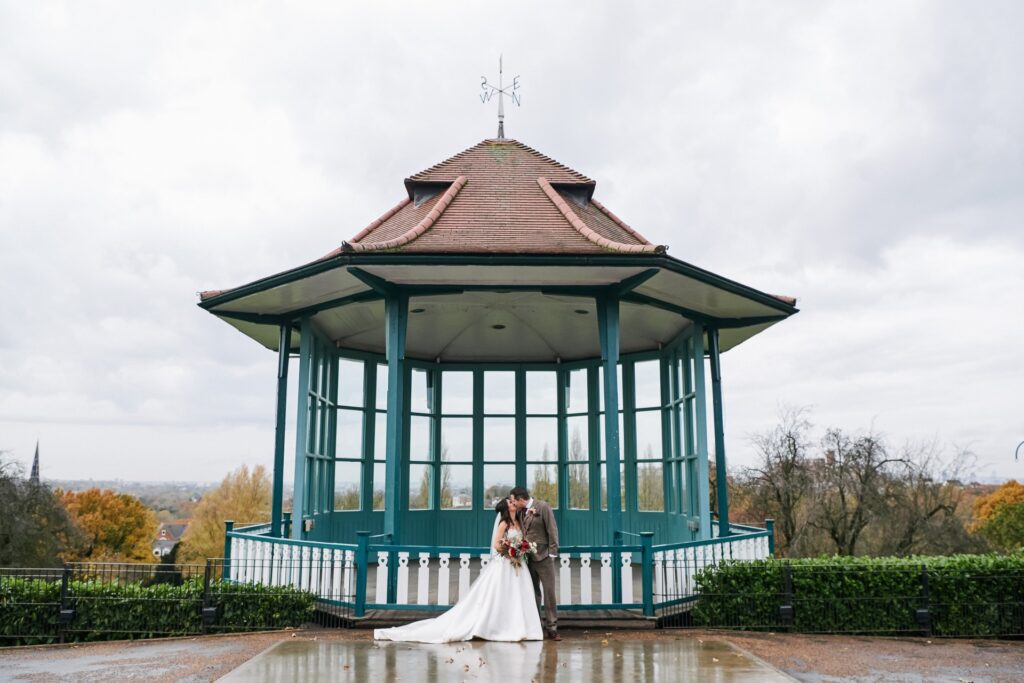 bride and groom in front of the bandstand at The Horniman museum. 