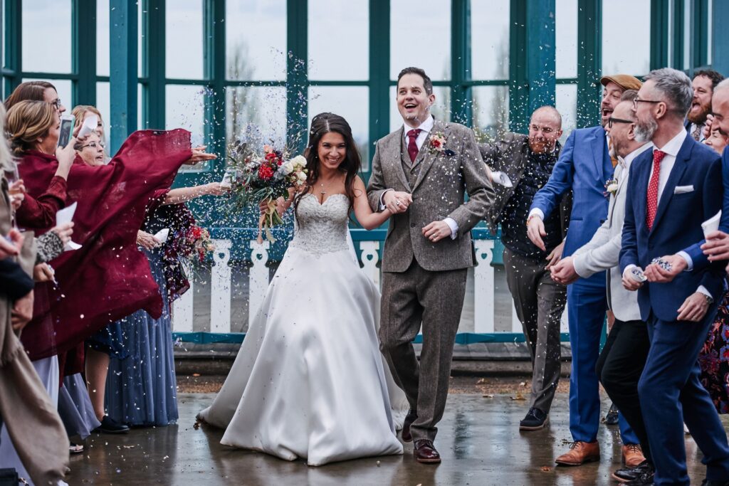 bride and groom walking through confetti during winter weddingThe Horniman museum. 