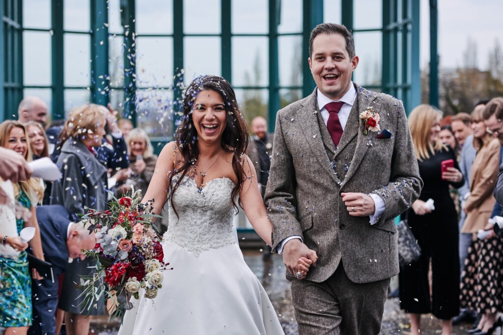 Bride and groom having confetti thrown over them during winter wedding