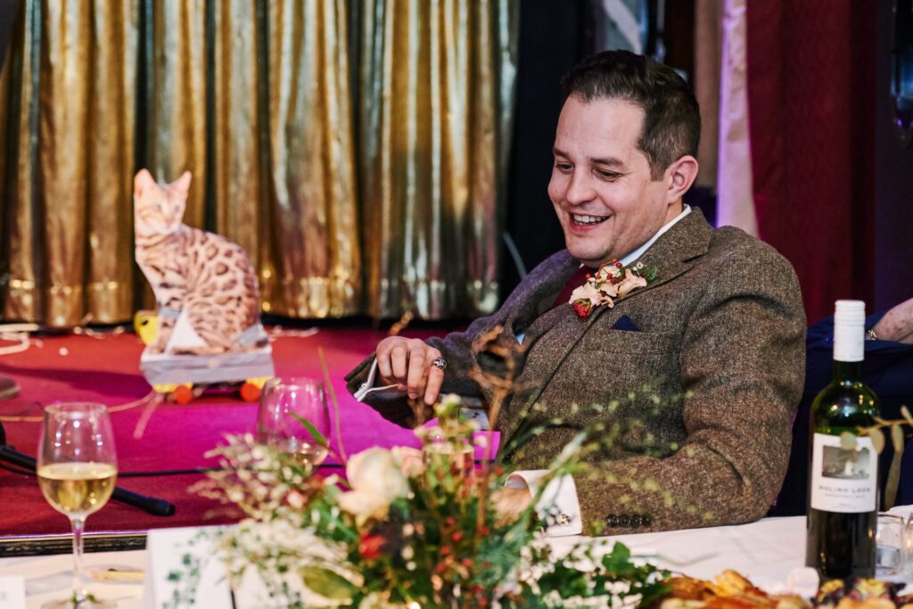 groom laughing during wedding speech with cardboard cat at Ivy House pub