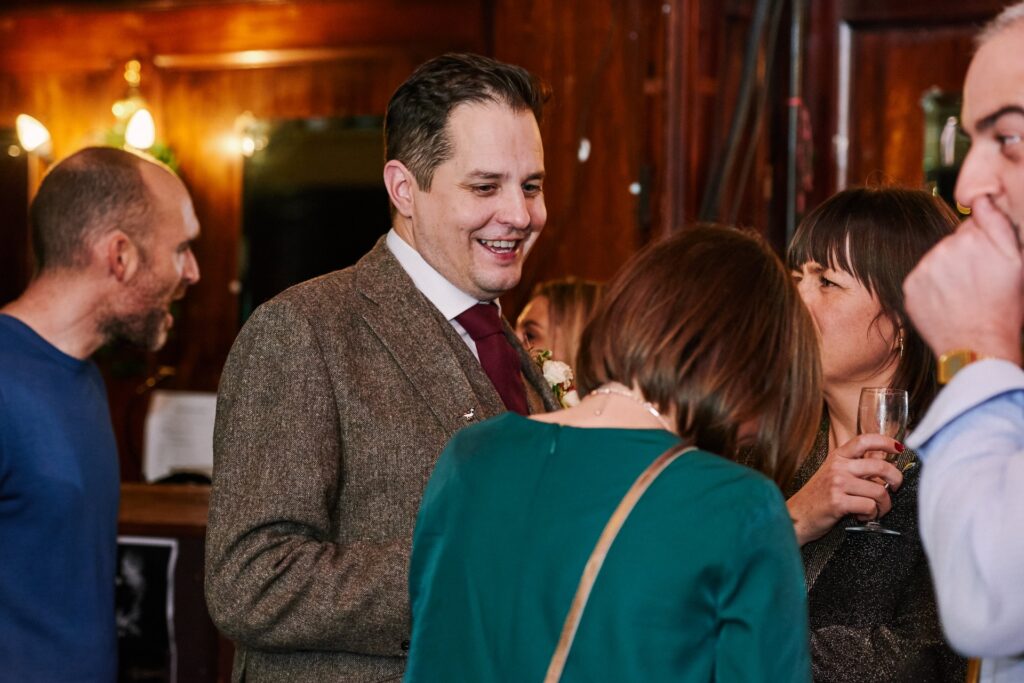 groom laughing whilst socialising with wedding guests